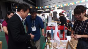 さいたま市民ネットワークのブースで説明を聞く清水さいたま市長